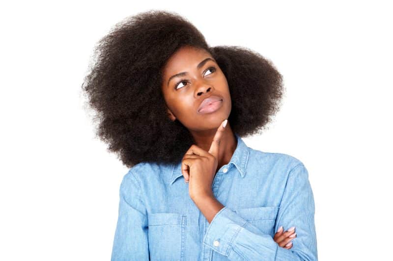 Close up horizontal portrait of thinking young black woman with afro looking up at copy space