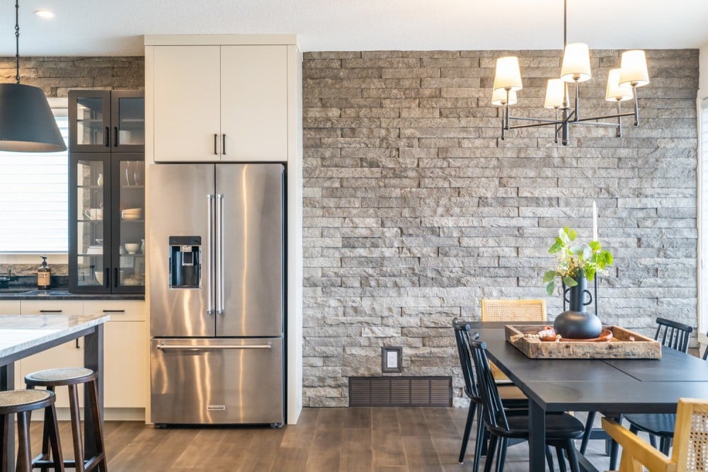 Kitchen with grey brick wall and steel refrigerator Cuisine avec mur de briques grises et réfrigérateur en acier.