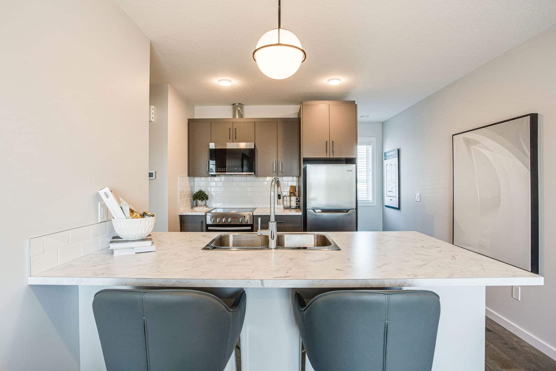 white and grey kitchen with brown kitchen cupboards and grey chairs / Cuisine blanche et grise avec armoires de cuisine brunes et chaises grises.