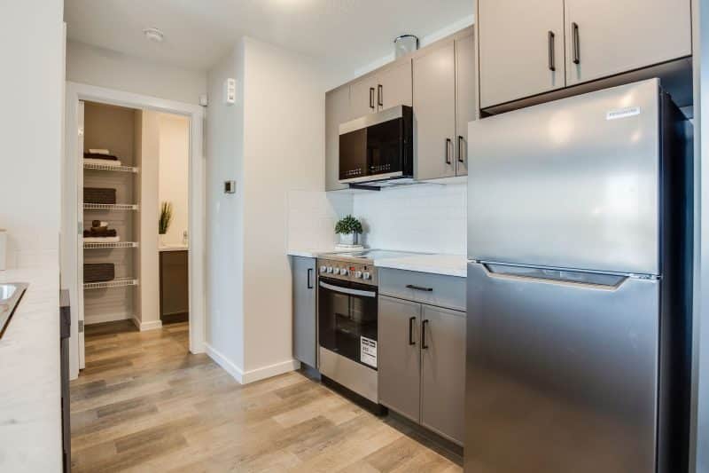 Hardwood floor in kitchen and grey kitchen cabinets with stainless steel fridge