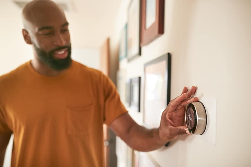 Man changing thermostat / Homme changeant le thermostat