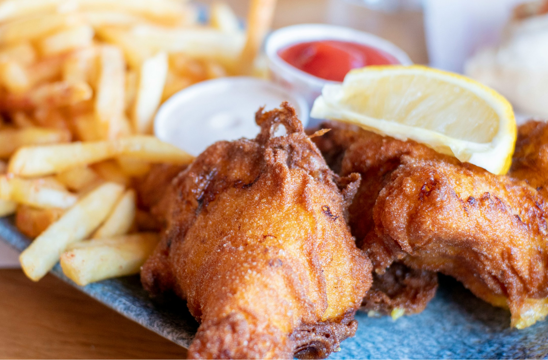 A close up of fish and chips with a lemon wedge. Gros plan sur un plat de poisson-frites accompagné d’un quartier de citron.