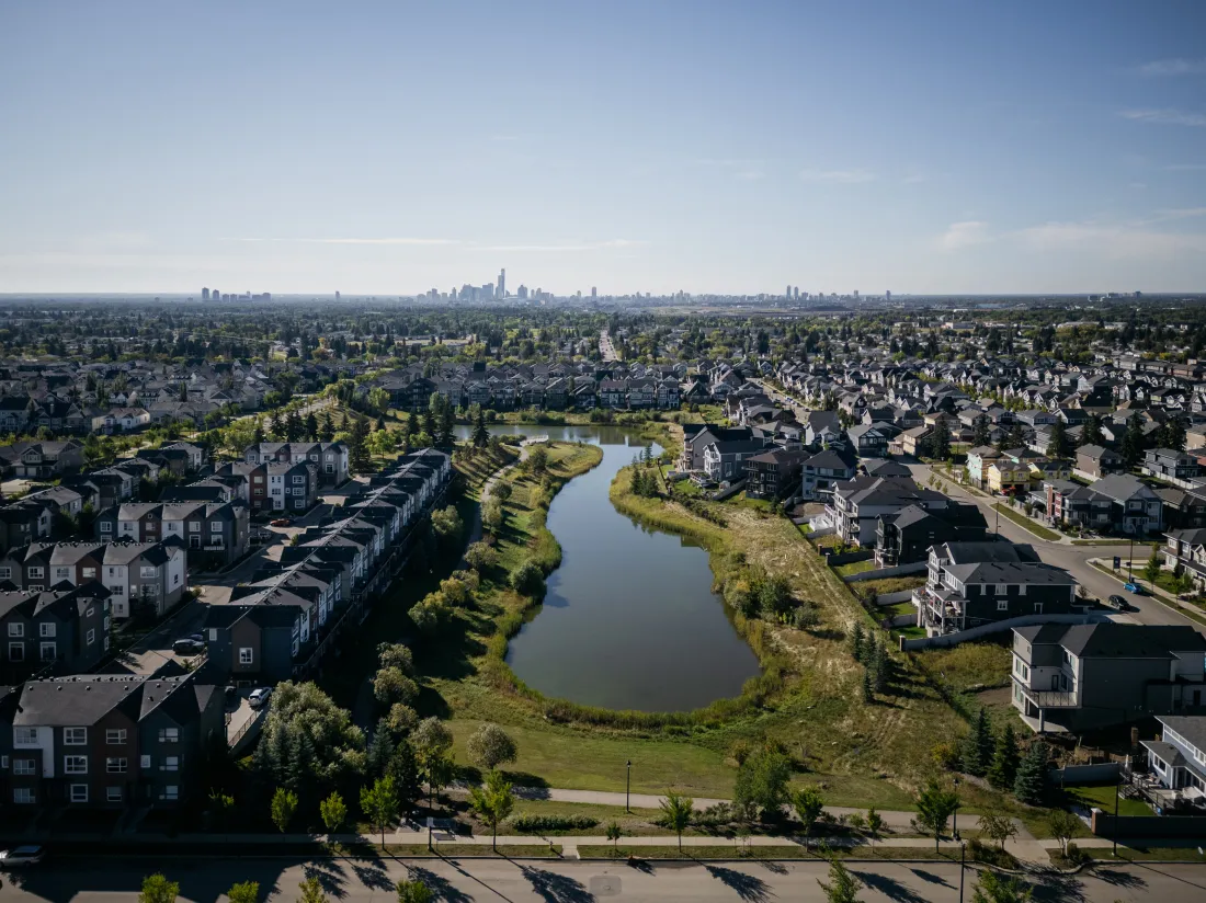 Aerial view of Bedford Basin and the surrounding homes with Edmonton downtown on the skyline from Village at Griesbach