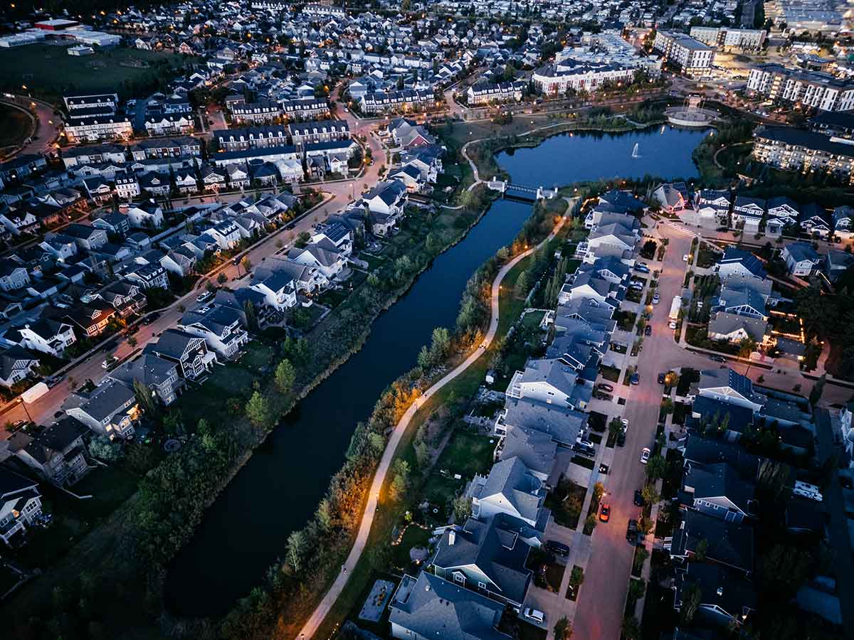 Aerial view of a suburban neighborhood with houses, streets, and a canal at dusk.